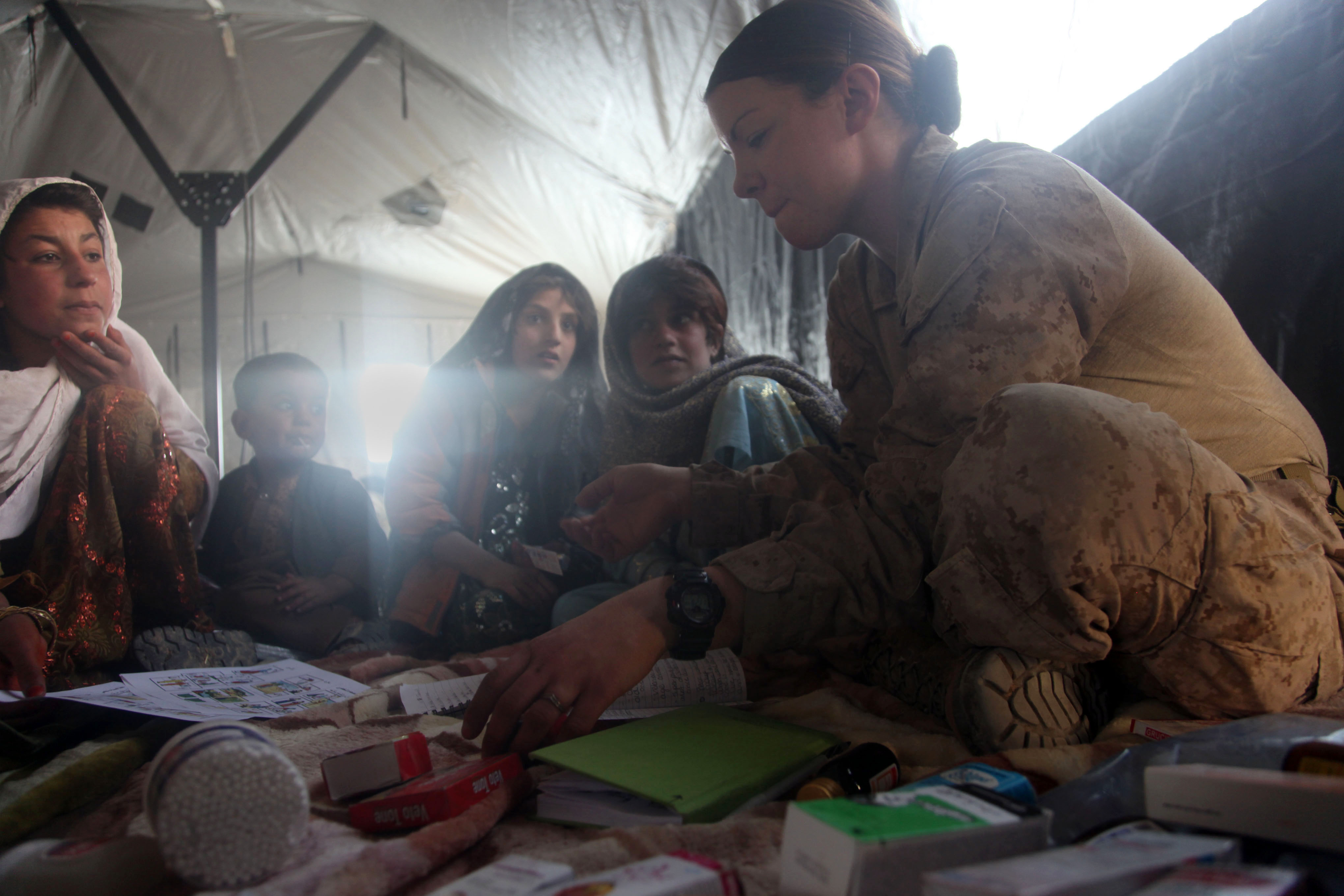 Navy medic works with Afghan children during a health training initiative.