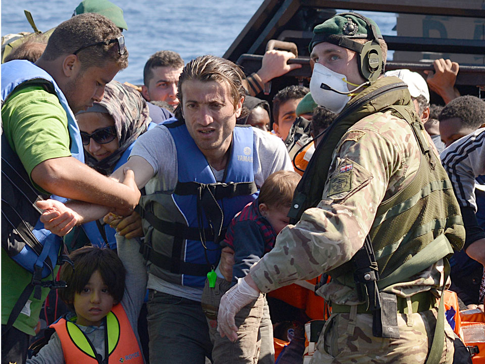 The sailors and Royal Marines of HMS Bulwark help migrants ashore
